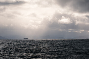 Obraz premium View of a container ship off the Norwegian coast in sunlight.