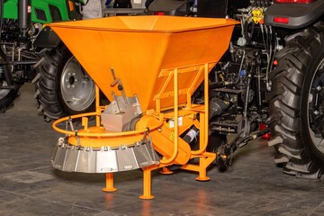 Innovative orange spreader stands ready for efficient farming in a bustling agricultural expo