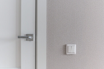 A white interior door with a sleek metallic handle; adjacent to a light grey textured wall with a...