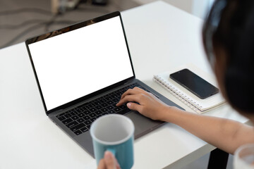 Home Office. Young professional working on laptop with coffee cup in hand.
