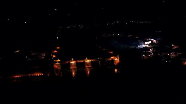 Fast aerial push over illuminated dam at night
