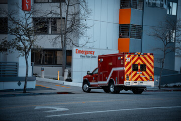 Red ambulance parked outside a hospital emergency room entrance with chest pain center sign © Tom Harwood