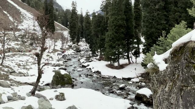 Scenic natural beauty of Chandanwari Valley featuring rocky landscapes, flowing streams, snow patches, and majestic Himalayan mountains near Pahalgam, Kashmir.