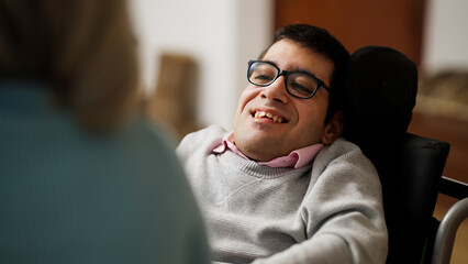 Man with physical disability in a wheelchair smiling, engaging in a conversation at home, fostering inclusion and positive well being