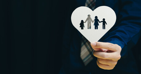 health insurance concept. Person holds heart shaped cutout featuring silhouettes of family, symbolizing love and unity. image conveys warmth and togetherness