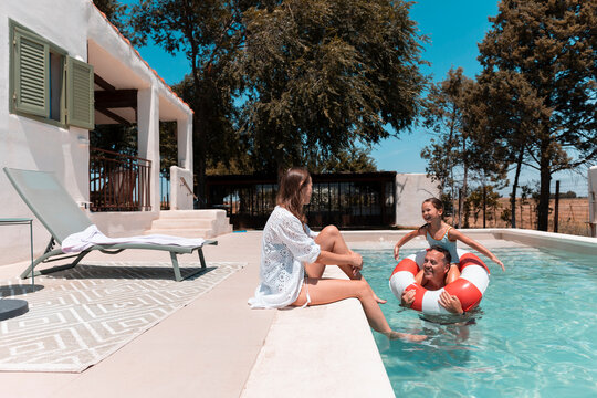 Family enjoying summer vacation day by swimming pool