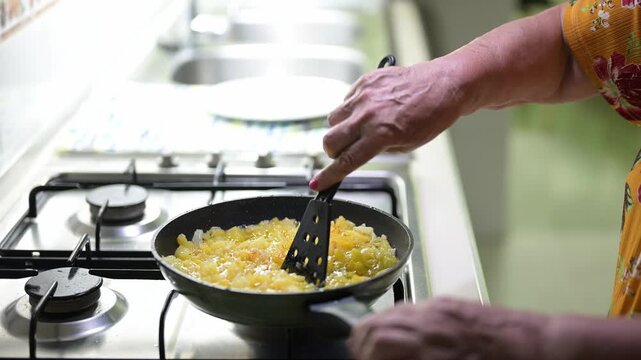 Older woman preparing a Spanish omelette in the kitchen.