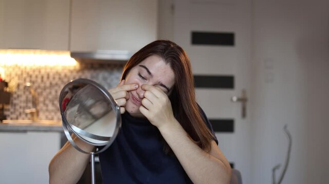 Young woman squeezes blackheads on face in mirror ruining fresh look frustrated by clogged pores home skincare habit realistic beauty moment daily routine stress acne skin