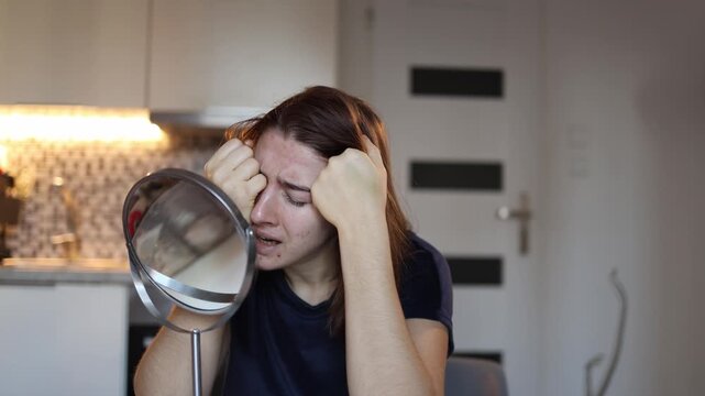 Young woman cries in front of mirror overwhelmed by reflection she dislikes feeling insecure and broken struggling with self worth quiet home emotional moment
