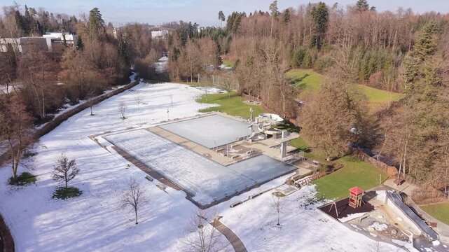A swimming pool in dormancy, completely frozen over in a serene and snowy winter setting.