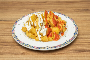 Patatas bravas where the brava sauce and mayonnaise have been mixed to form a pink sauce, completely coating the potatoes.