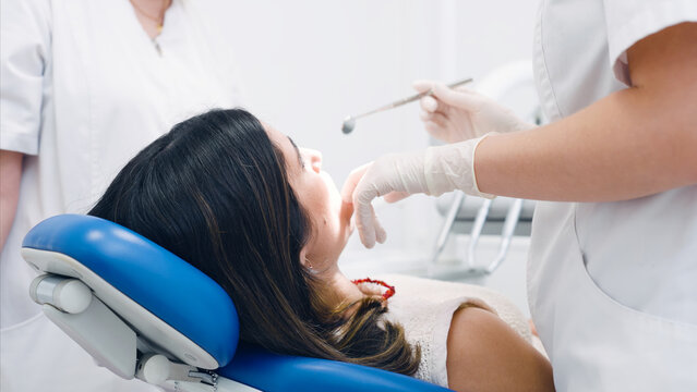 Dentist in protective gloves checking a patient's mouth with dental tools during a routine oral hygiene examination at a clinic