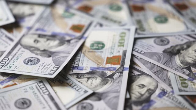 Macro view of hundred dollar banknotes highlighting fine details, security elements and paper texture, representing money, wealth accumulation and financial stability.