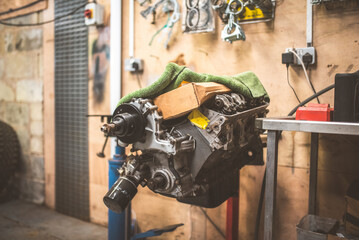 Automotive engine repair in a workshop setting with tools and parts visible
