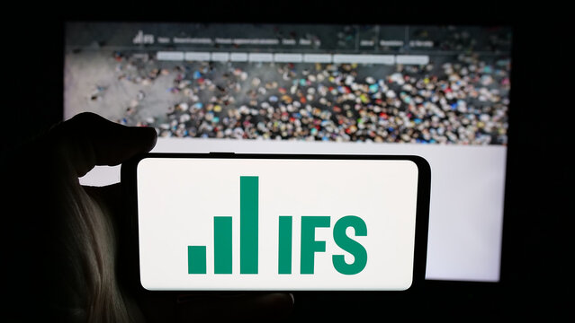Stuttgart, Germany - 01-30-2026: Person holding cellphone with logo of British Institute for Fiscal Studies (IFS) on screen in front of webpage. Focus on phone display.