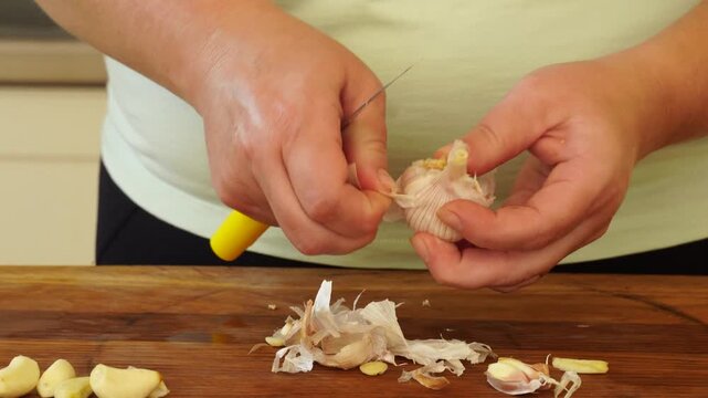 Woman is peeling and cutting garlic for cooking
