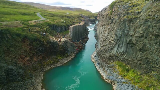 A scenic view of Studlagil Canyon in Iceland with basalt columns and a river.