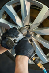 Mechanic unscrews a nut on a wheel rim