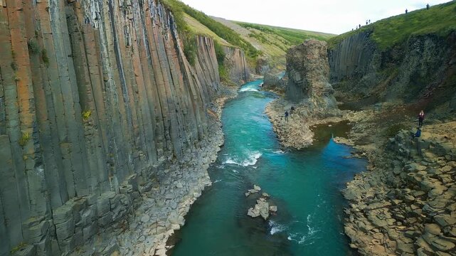 A scenic view of Studlagil Canyon in Iceland with basalt columns and a river.