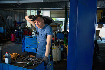 Mechanic wipes sweat from his forehead in the workshop