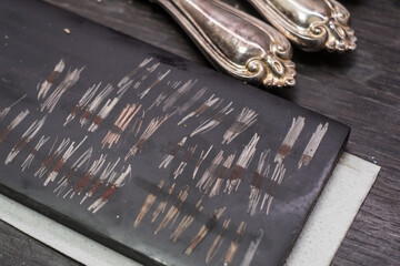 Testing gold and silver using touchstone and acid reagents. Traditional non-destructive, low-damage method to determine karat purity of gold and silver.