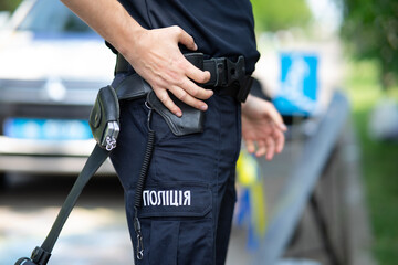 Ukrainian patrol police officer in dark blue trousers with "Police" lettering, demonstrating a tactical duty belt with professional equipment.