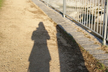 柵沿いの砂利道に映る影の光景