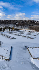Fototapeta premium Ithaca, NY, USA. 01-30-2026 Vertical winter aerial photo of frozen, snowy marina, docks at Allan H Treman State Marine Park,