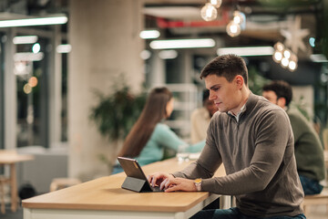 Fototapeta premium Young man typing tablet at modern workspace