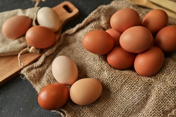 Farm fresh brown and white eggs arranged on burlap with wooden cutting board in background