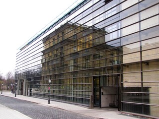 Modern glass facade of the Max Planck Institute for Innovation and Competition in Munich, reflecting historic surroundings and symbolizing the dialogue between contemporary research and tradition,2011