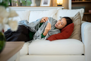 Obraz premium Young woman checking thermometer at home feeling unwell