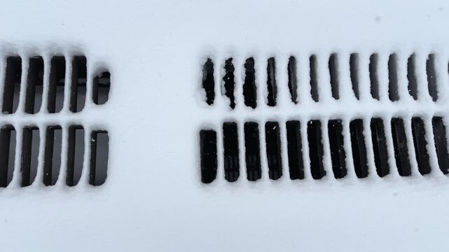 Cast iron drainage grates covered with snow during snowfall