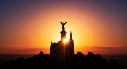 Fototapeta premium Sunset behind an angel statue and church building silhouette on a hilltop. Religious architecture for Palm Sunday worship and spirituality.