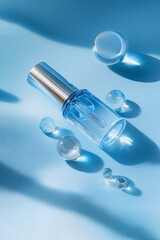 Blue cosmetics serum bottle with pipette and clear water spheres on a light blue background, highlighting hydration and skincare