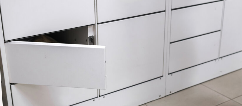 Contactless delivery: a woman uses smartphone to open a smart parcel locker for click-and-collect pickup. Modern last-mile e-commerce self-service returns and 24/7 convenience for urban shoppers now.