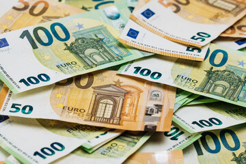 Obraz premium Close-up view of assorted Euro banknotes including 50 and 100 denominations arranged in a layered pattern on a flat surface