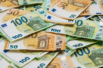 Obraz premium Close-up view of assorted Euro banknotes in denominations of 50 and 100 euros spread out on a flat surface, showcasing intricate designs and colors