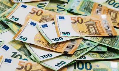 Obraz premium Close-up view of assorted Euro banknotes including 50 and 100 denominations arranged on a flat surface, showcasing detailed designs and colors of currency