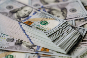 Stacks of hundred-dollar bills arranged neatly on a surface, showcasing the intricate details of the currency and the vibrant colors of the banknotes
