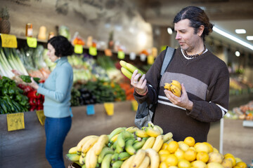 Obraz premium Male shopper carefully selects fresh bananas in a grocery supermarket