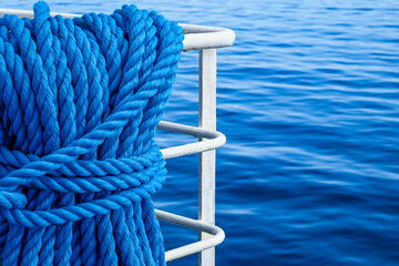 Une corde bleue enroul&eacute;e est attach&eacute;e &agrave; une rambarde m&eacute;tallique surplombant une mer calme