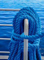 Une corde bleue enroul&eacute;e est attach&eacute;e &agrave; une rambarde m&eacute;tallique surplombant une mer calme