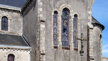 Close-up of Gothic windows on a stone church wall featuring a decorative cross, highlighting intricate architectural detail.