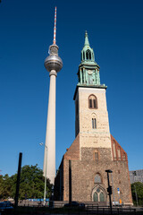 Berlin, germany, august 11, 2023. Berlin tv tower, fernsehturm, standing next to st. Mary's church, marienkirche, representing a blend of old and new architecture
