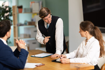 Obraz premium Business partners are sitting at table and listening to man colleague. Discussion of current situation, company working session, skull session or council