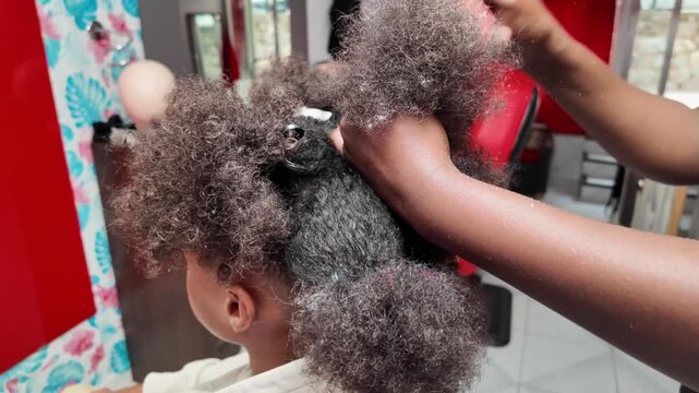 Close-up rear view of stylist&rsquo;s hands combing and sectioning afro hair to prepare for braiding