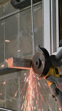 Angle grinder cutting metal bar with bright sparks in workshop close-up