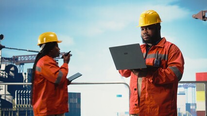 African american worker on offshore platform deck configuring derrick management systems for more...