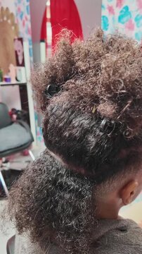 Rear view of stylist marking precise lines on teen boy&rsquo;s afro hair for even braiding sections